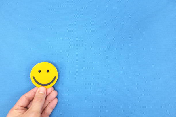 istock Hands holding a yellow smiley face in blue background with copy space. Positivity and happiness concept. 1250120067