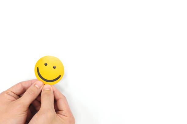 Hands holding a yellow smiley face in white background with copy space. Positivity, good customer feedback and happiness concept.
