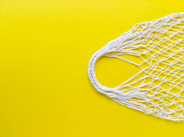 istock White string cotton eco bag on yellow background. Simple flat lay with copy space. Ecology zero waste concept. Stock photo. 1250120087