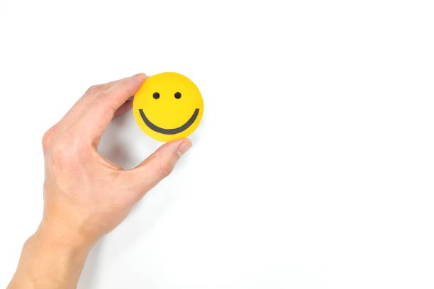 istock Hands holding a yellow smiley face in white background with copy space. Positivity and happiness concept. 1250120090