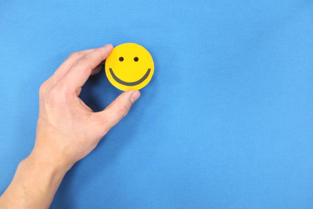 istock Hands holding a yellow smiley face in blue background with copy space. Positivity and happiness concept. 1250120149