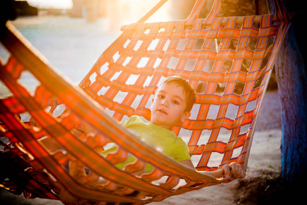 istock Little boy lies in a hammock on nature at sunset 1250121132