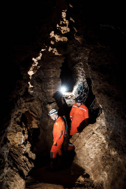 istock Two men, strong physique, explore the cave. Men dressed in special clothes to pass through the cave and stopped, looking at the map 1250125548