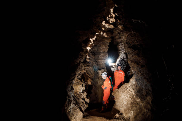 istock Two men, strong physique, explore the cave. Men dressed in special clothes to pass through the cave and stopped, looking at the map 1250128049
