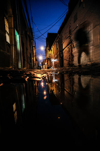 istock Dark alley shadows reflected in puddle - Hoboken, NJ 1250129664