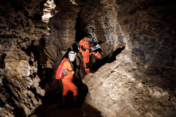 istock Two men, strong physique, explore the cave. Men dressed in special clothes to pass through the cave and stopped, looking at the map 1250130198