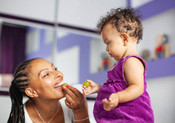 ブドウを食べるアフリカ系アメリカ人の母と赤ちゃんの女の子 - family grape ストックフォトと画像