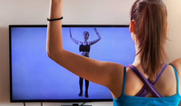 Young woman exercising and watching online workout video