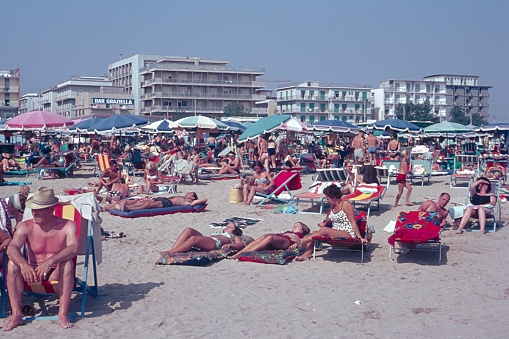 Rivazzurra, Rimini, Emilia-Romagna, Italy, 1966. Start of mass tourism. Full beach with Central European tourists and locals on the Adrian Sea coast. Also: beach umbrellas, deck chairs and hotels.