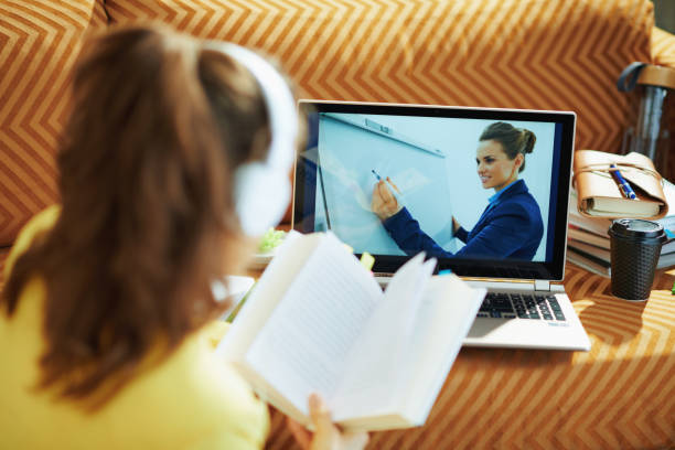 istock woman with white headphones and textbook using online school 1250137921