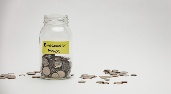 A glass jar holds many quarters, dimes and nickels for an emergency.