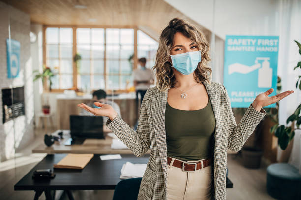istock Beautiful woman with protective mask standing in office 1250138721