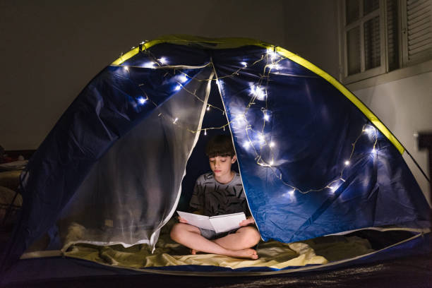 istock Boy reading a book at night home camp 1250139144