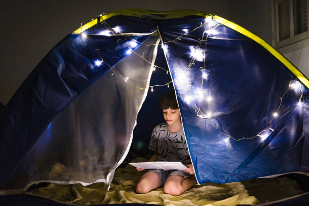 Boy kneeling reading a book at home camp