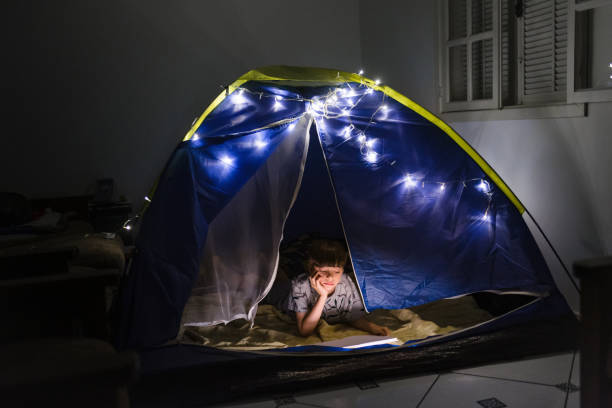 istock Boy alone reading a book at home camp at night 1250139201