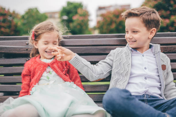 istock Brother and sister sitting on a park bench together 1250140436