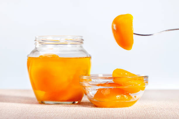 istock Canned peach halves in bowl and jar on the table. 1250143853