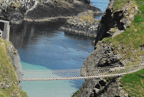 Overview of gorgeous coast and the renowned 20 meter long Carrick-a-Rede rope walking bridge which connects the mainland to beautiful Carrick island on the North West coast of Ireland.