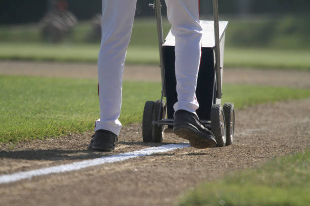 l’entraîneur dessine la ligne de base avec le marqueur de ligne sèche - baseball diamond baseball baseline grass photos et images de collection