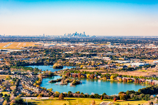 Suburban Houston Texas aerial with homes surrounding a lake and the skyline of the city in the distant background.