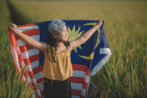 malaysia independence day an asian chinese young girl wrapped with malaysia flag at padi field enjoying morning sunlight and feel proud and happy