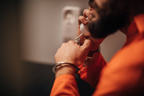 istock Male prisoner talking on phone in prison visit room 1250158402