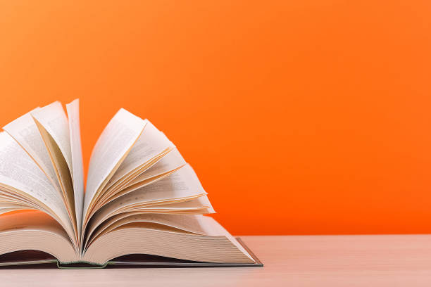 istock The book is open, lying on the table, sheets fanned out on a orange background. 1250162819