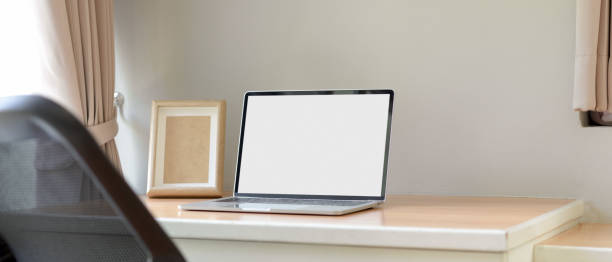 istock Simple worktable with blank screen laptop and mock-up frame on wooden table in bed room 1250165108
