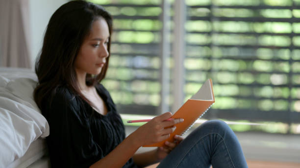 istock Female freelancer looking on her schedule book while sitting on floor at bedroom 1250165126