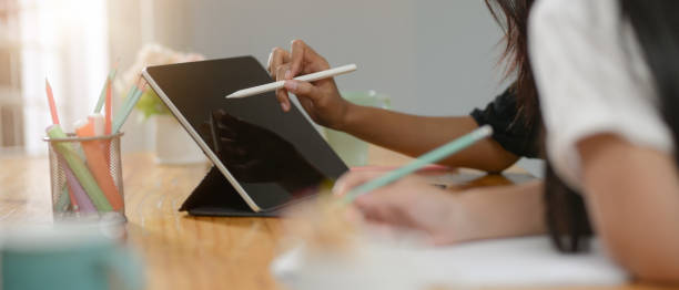 istock Two college students doing their assignment together with digital tablet and stationery on wooden table 1250165238