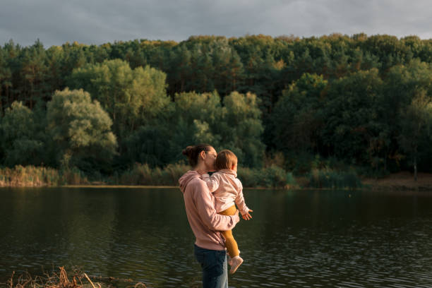 matka i dziewczynka siedzi w pobliżu jeziora. podróże lokalne. nowe normalne wakacje. dzień matki - homegrown produce environment green forest zdjęcia i obrazy z banku zdjęć