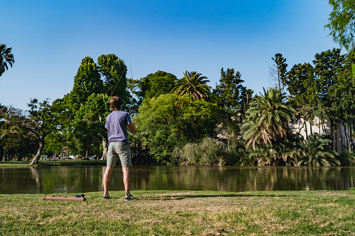 Argentinian teenage boy fishing in lake in public park, Buenos Aires, Argentina.