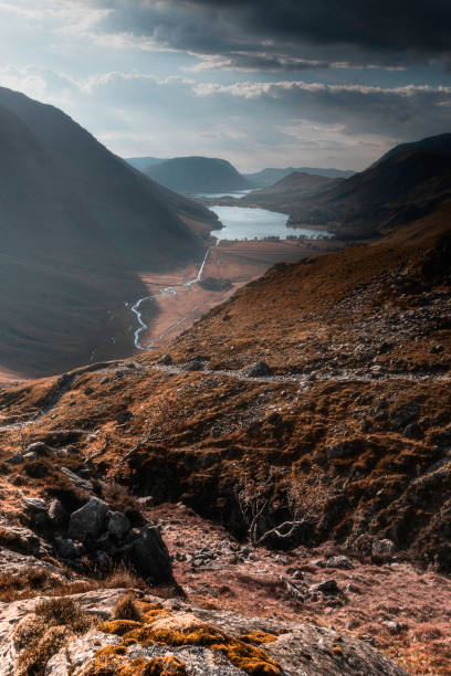 View on Buttermere lake from Warnscale bothy.Idyllic autumn landscape scene with sunshine and dramatic, cloudy sky above mountain valley in Lake District, Cumbria, UK.
