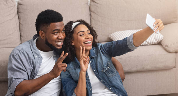 istock Happy african couple posing for selfie at home, using camera on smartphone 1250195400
