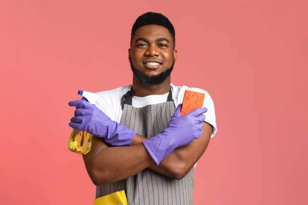 istock Confident Black Janitor Wearing Apron With Sponge And Spray Detergent In Hands 1250195459