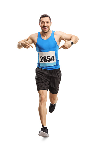 Full length portrait of a male athlete running and pointing at his race number isolated on white background