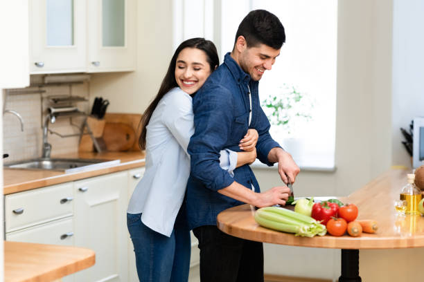 istock Lovely couple preparing dinner cutting vegetables at home 1250198520