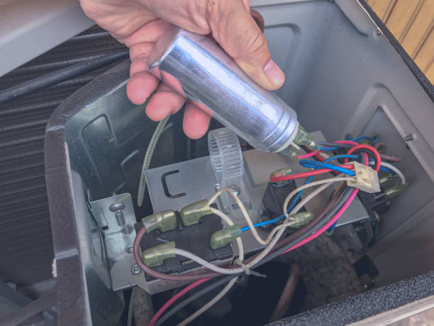 reparo do ar condicionado pelo técnico. o técnico substitui a capacidade de ar condicionado. mão segurando a corrida do capacitor. - condensador componente elétrico - fotografias e filmes do acervo