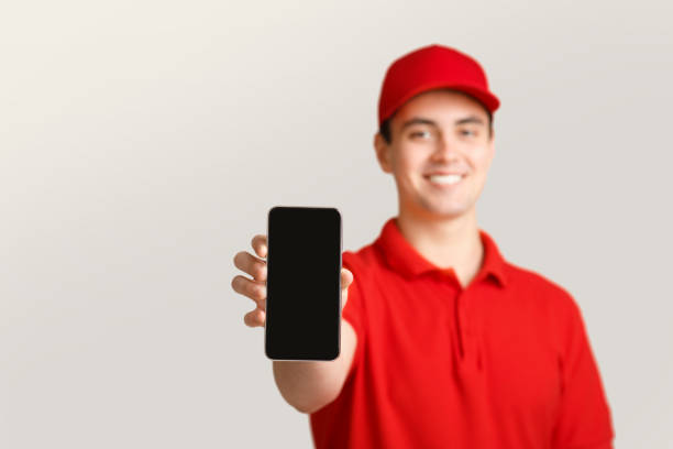 istock Modern post and online application. Deliveryman shows smartphone with blank screen. 1250200241