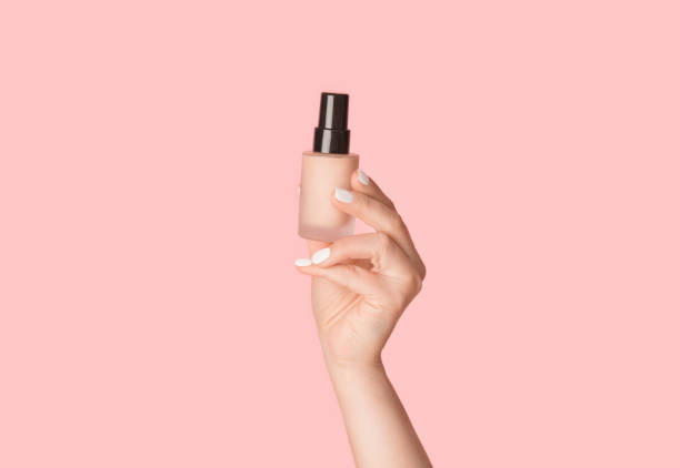 skin care concept. millennial lady holding bottle of natural concealer on pink background, closeup - moisturizer cosmetics merchandise human hand imagens e fotografias de stock