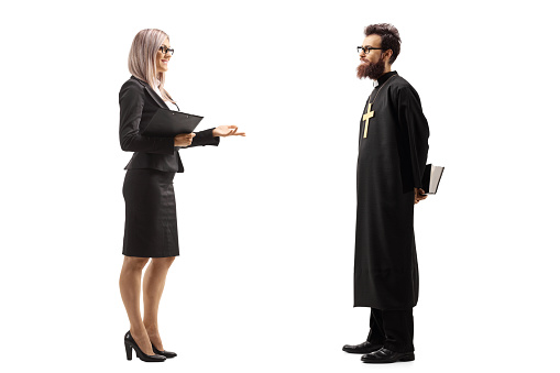 Full length profile shot of a businesswoman standing and talking to a catholic priest isolated on white background