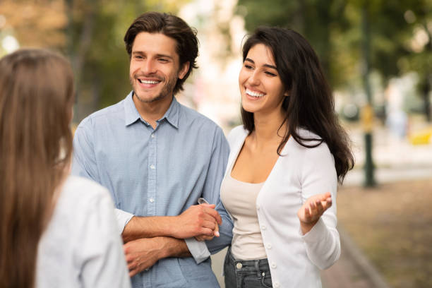 married couple meeting single female friend walking outdoor in park - former imagens e fotografias de stock