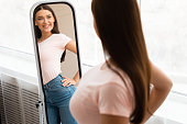 istock Happy Skinny Girl Looking At Reflection In Mirror At Home 1250203485