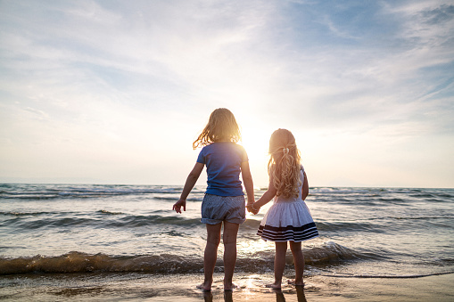 Two girls playing near sea at sunset