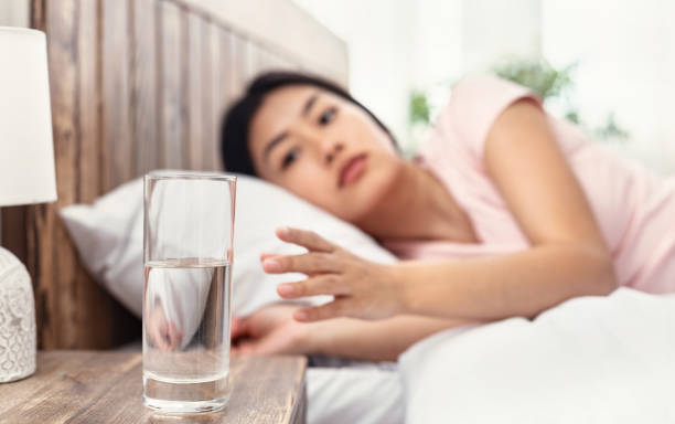 Chinese Girl Drinking Water In Morning Lying In Bed Indoor Chinese Girl Drinking Water In The Morning Starting Day With Hydration And Healthy Liquid Lying In Bed Indoor. Selective Focus wake water stock pictures, royalty-free photos & images