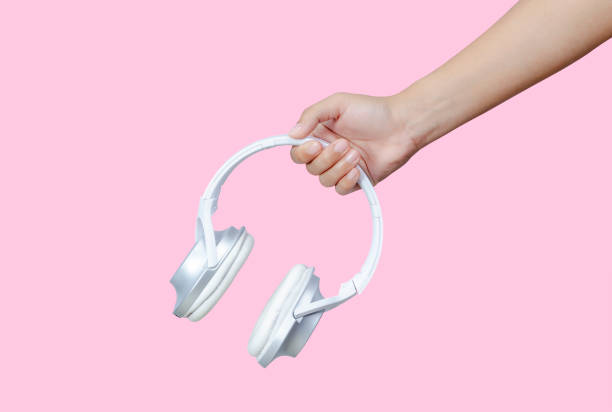 istock Female hands holding white headphones on pink background. 1250204936