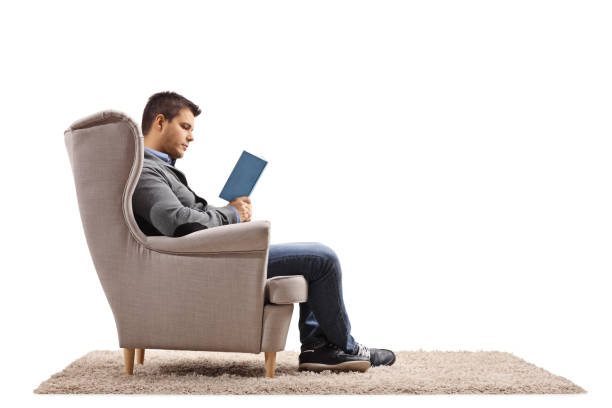 młody mężczyzna siedzący w fotelu i czytający książkę - sitting young men book isolated on white zdjęcia i obrazy z banku zdjęć