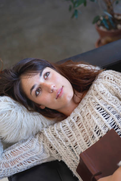 istock Tired young woman lying on a sofa with a book 1250205652