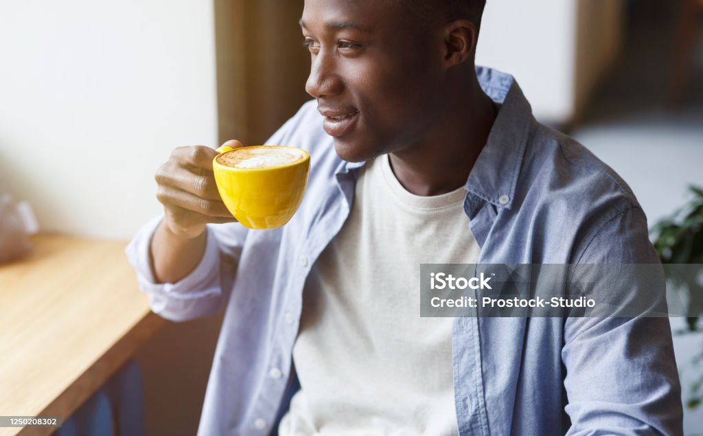 African American man drinking his moring coffee and relaxing in cafe. Panorama African American man drinking his moring coffee and relaxing in city cafe. Panorama Coffee - Drink Stock Photo