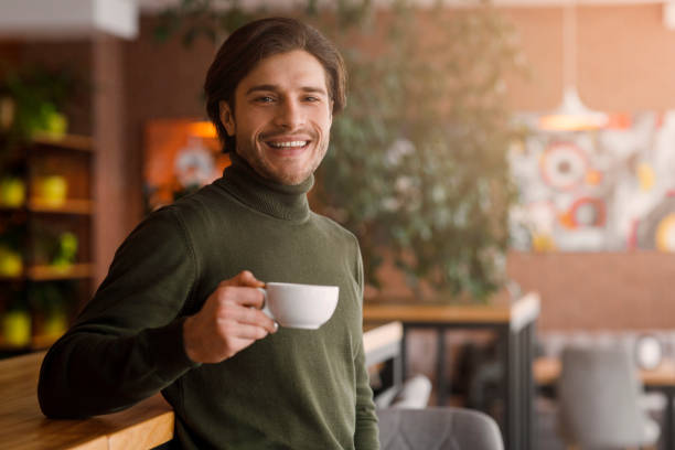 istock Young man standing at cafe and drinking coffee 1250208497
